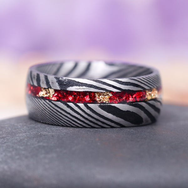 Crushed Red Garnet and Gold Leaf Wedding Band- 8MM Damascus Steel by Aquamarise, featuring a textured black and silver Damascus steel band with a vivid inlay of crushed red garnet and gold leaf, part of Men's Wedding Bands and January Birthstone Jewelry collections.