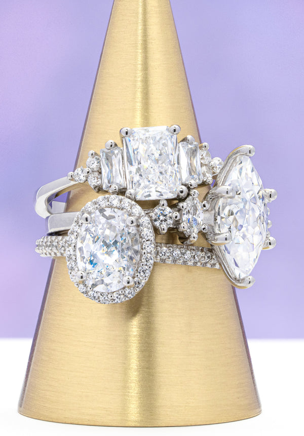 Three diamond rings on a gold stand against a purple background