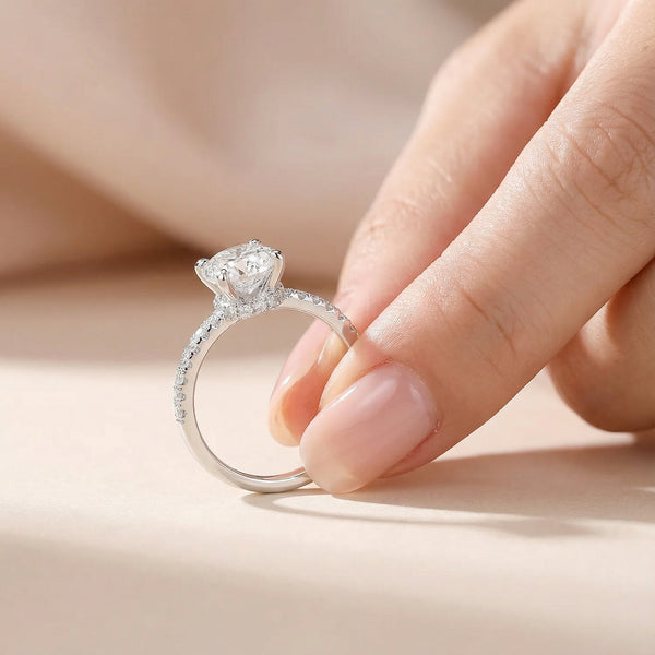 Diamond ring being held between fingers on a neutral background