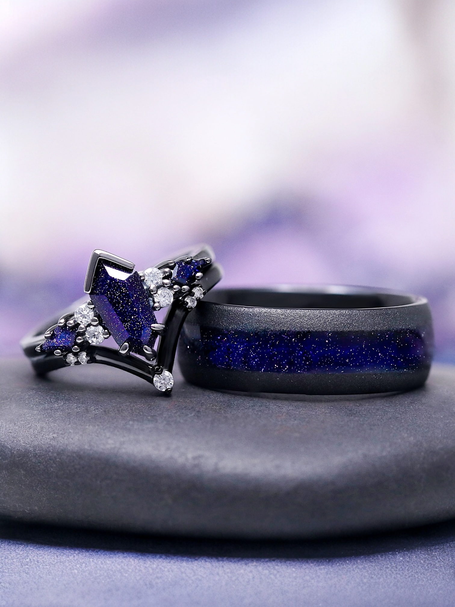 Two rings with purple gemstones on a gray surface with a blurred purple background
