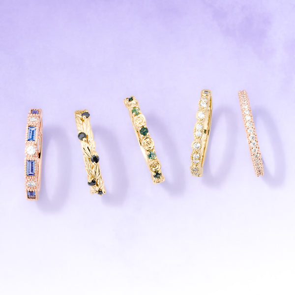 Set of gold rings with gemstones on a light purple background