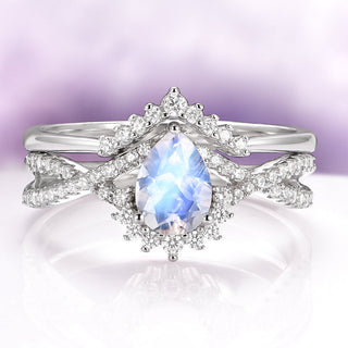 Pear-cut moonstone with a blue glow in a halo of white stones, on a twisted pavé band with a crown-shaped stacking band in sterling silver
