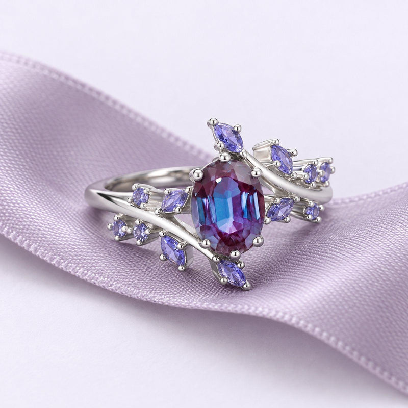 Silver alexandrite fairy leaf ring with lavender sapphire accents resting on a long lavender silk ribbon that extends out of frame.