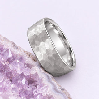 Hammered silver-tone tungsten wedding band resting beside a cropped pale lavender geode on a soft lilac ground.