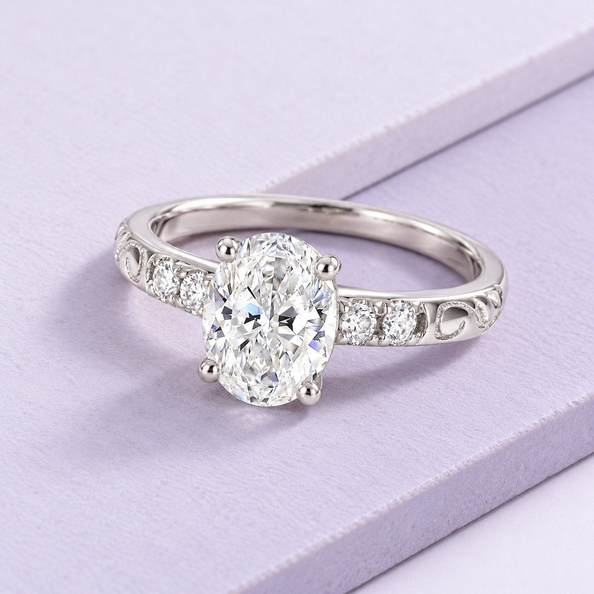 Oval lab-grown diamond ring with open white-gold filigree and clear side stones, angled naturally across pale-lilac tiles.