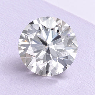 Round brilliant loose lab-grown diamond resting naturally on fine lilac cotton paper, photographed in soft daylight.