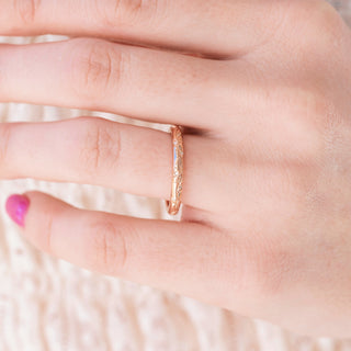 Rose gold 2mm wedding band with floral design on hand over a light background 