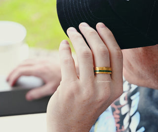 Man wearing the Victoria Vintage Emerald Couples Ring Set by Aquamarise, showing a hammered gold band with green emerald detail on the ring finger.