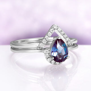 Silver ring with a purple gemstone on a white surface with a purple gradient background