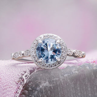 Art Deco Aquamarine Engagement Ring by Aquamarise, styled on soft pink fabric to show the aquamarine halo and slender band.