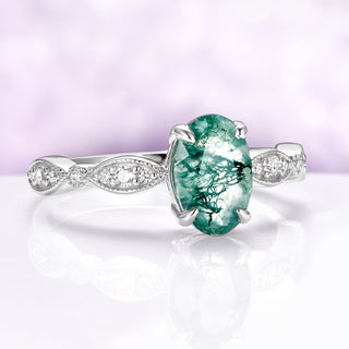 Ring with a green gemstone and silver band on a white background