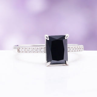 Angled view of the emerald cut black onyx ring showing the four-prong basket and pavé-set shoulder stones