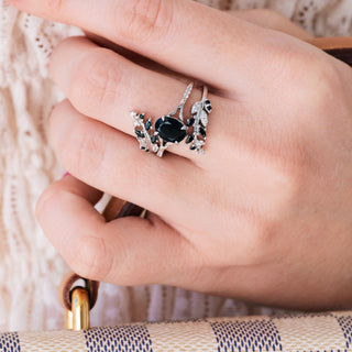White gold ring set with oval cut natural black onyx center stone and accents on hand over a light background