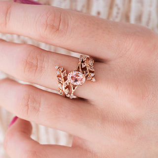 Rose gold ring set with oval cut morganite center stone and accents on hand over a light background