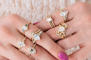 Yellow gold engagement rings with diamonds on hands over light background 