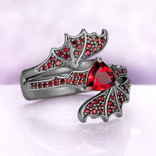 Angled view of the bat wing set showing the garnet pavé along each wing and the trillion center