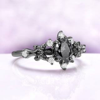 Angled view of the Carmilla gray moissanite ring showing the scrollwork shoulders and clear moissanite accents against the dark finish
