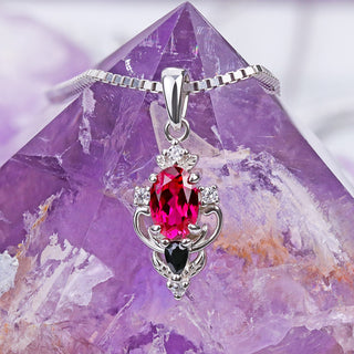 Carmilla lab-grown ruby and black onyx pendant on its sterling box chain draped over an amethyst crystal