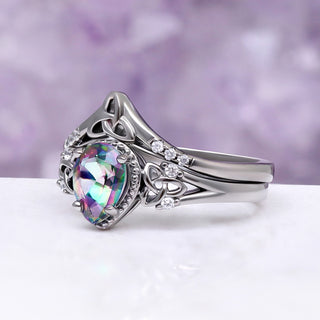Celtic Knot Mystic Topaz Ring Set in Black by Aquamarise, shown on a lilac geode with the rainbow mystic topaz centre.