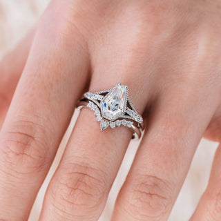 White gold engagement ring set with coffin cut diamond center stone and accents on hand over a light background 