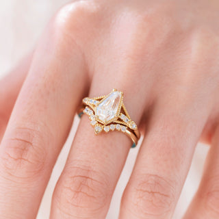 Yellow gold engagement ring set with coffin cut diamond center stone and accents on hand over a light background 
