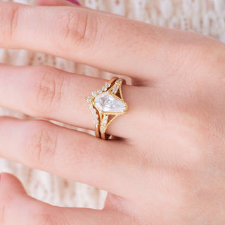 Yellow gold engagement ring set with coffin cut diamond center stone and accents on hand over a light background 