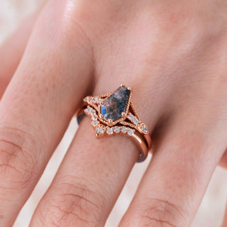 Rose gold engagement ring set with coffin cut Herkimer diamond center stone and accents on hand over a light background 