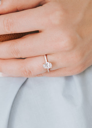 Close-up of a hand wearing a diamond ring on a neutral background
