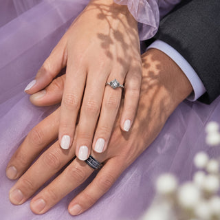 Couple's hands resting on lilac tulle wearing the Esme Gray Moissanite and Meteorite Couples Ring Set by Aquamarise, her gray moissanite ring above his meteorite tungsten band