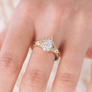 Yellow gold engagement ring set with oval cut diamond center stone and accents on hand over light background