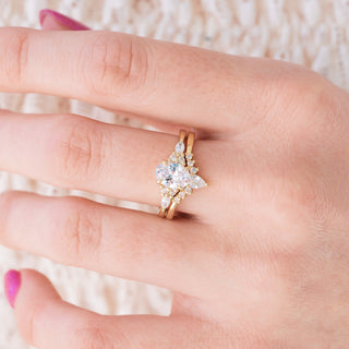Yellow gold engagement ring set with oval cut diamond center stone and accents on hand over light background