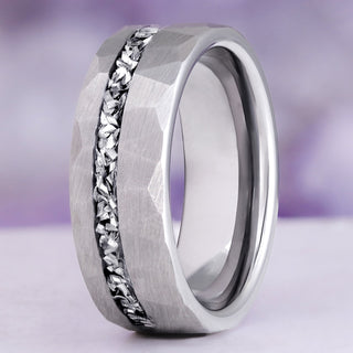 Close-up of the Galaxy Meteorite Men's Wedding Band in Silver Tungsten Carbide (8mm) by Aquamarise standing upright, faceted hammered finish around the crushed meteorite channel