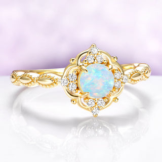 Gold ring with a central opal stone and diamond accents on a light purple background