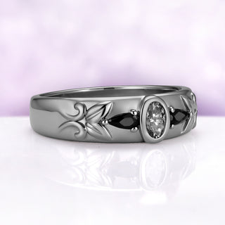 Angled view of the gray moissanite and black onyx band, showing the leaf and vine carving on the shoulder of the 6 mm dome