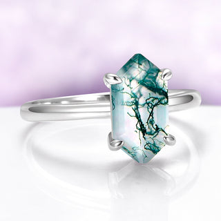 Silver ring with a unique green and white stone on a light purple background