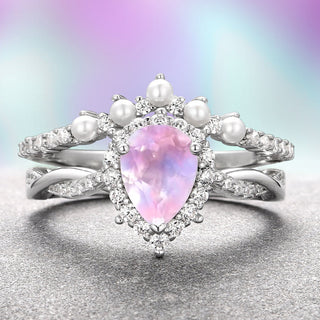 A sterling silver ring with a pear-shaped rose quartz center stone, accompanied by round white accent stones and a band of pearls.