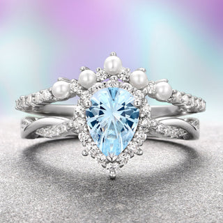 A sterling silver ring with a teardrop-shaped aquamarine centerpiece and round accent stones, accompanied by a pearl band.