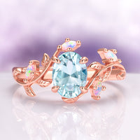 Aquamarine & Fire Opal Leaf Engagement Ring in 14K Solid Rose Gold by Aquamarise Gold, featuring an oval aquamarine center with white fire opal accents on a rose gold leaf-inspired band.