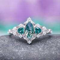 Elain Moss Agate & Teal Sapphire Leaf Ring- 14K White Gold by Aquamarise Gold, featuring a marquise moss agate centerpiece flanked by teal sapphire accents on a delicate white gold band, part of nature-inspired and non-traditional engagement ring collections.