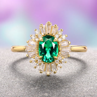 A vintage-inspired 14K yellow gold vermeil ring with a central green emerald simulated stone and accent stones arranged in a geometric pattern on a smooth band.