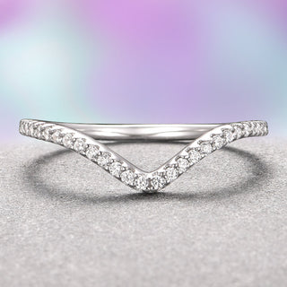 A 14K white gold chevron-shaped wedding band with petite moissanite stones set in a V-shaped arc on a textured background.
