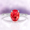 Oval Cut Padparadscha Sapphire Ring in Sterling Silver by Aquamarise featuring a vibrant orange oval sapphire flanked by pear-shaped white accents on a polished sterling silver band.