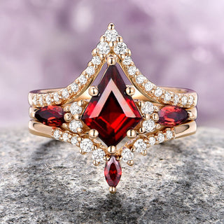 Elegant ring with red gemstone and diamonds on a textured surface with blurred purple background