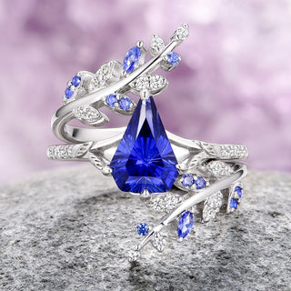 Two-piece leaf ring set with a shield-cut blue sapphire center stone and accent stones, crafted in 14K white gold, displayed on a rock.