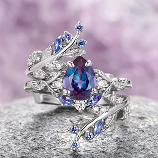 An elegant two-piece engagement ring set in 14K white gold featuring a teardrop-shaped lab-grown alexandrite centerpiece with accompanying leaf motifs and small accent stones.