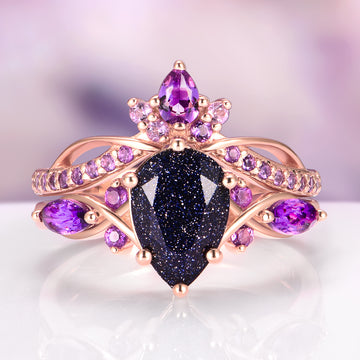 Feyra Starry Night & Amethyst Couples Ring Set featuring a pear-shaped dark blue sandstone center stone surrounded by vibrant amethyst gemstones set in a delicate rose gold band, crafted by Aquamarise for Matching Couples' Rings and February Birthstone collections.