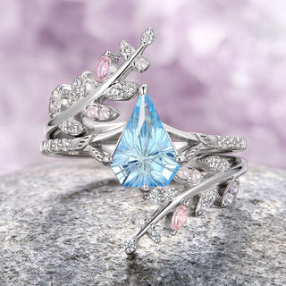A two-piece ring set with a shield-cut aquamarine center stone and rose quartz accents on a leaf motif band, crafted in 14K white gold.