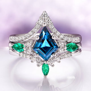 Elegant ring with blue gemstone and emerald stones on a reflective surface