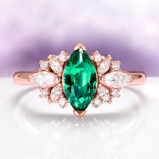 Rose gold ring with a green gemstone and white diamonds on a light purple background