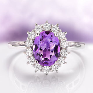 Ring with a purple gemstone and diamond halo on a light purple background